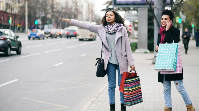 Two women hailing a taxi on city street